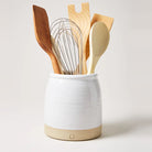 Farmhouse pottery beehive crock filled with cooking tools on a white background