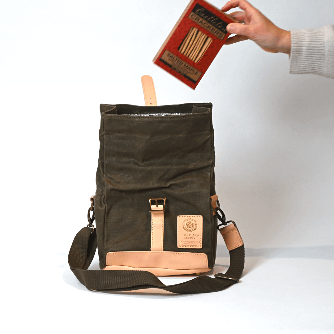 Coastland Supply Insulated Field Bag in Olive on a white background with someone putting meat and cheese in it.