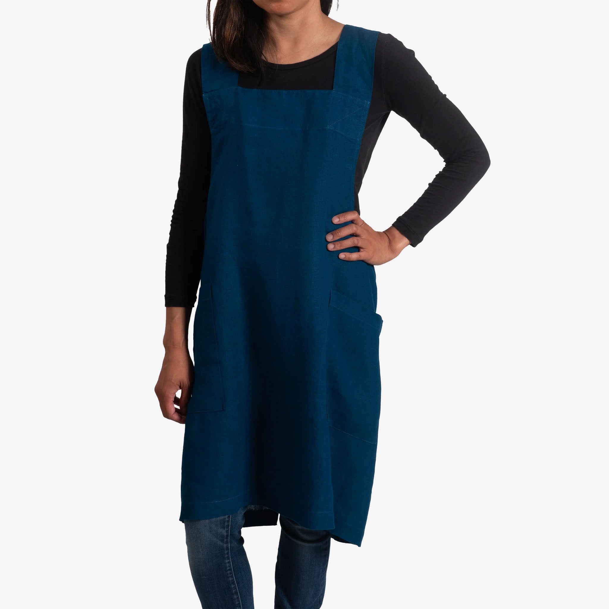 Person wearing a blue apron over a black long-sleeve shirt on a white background