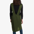 Person wearing a green apron over a black shirt on a white background