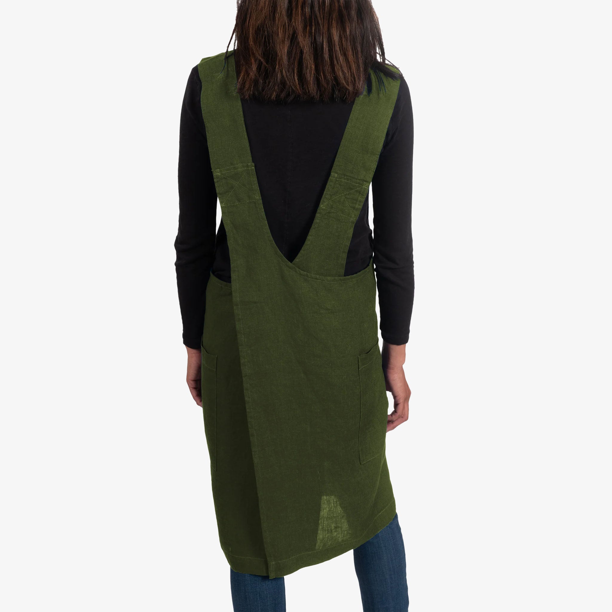 Person wearing a green apron over a black shirt on a white background
