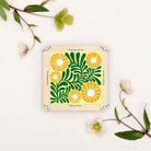 Flower press with image of yellow flowers and green vines painted on the front on a white background