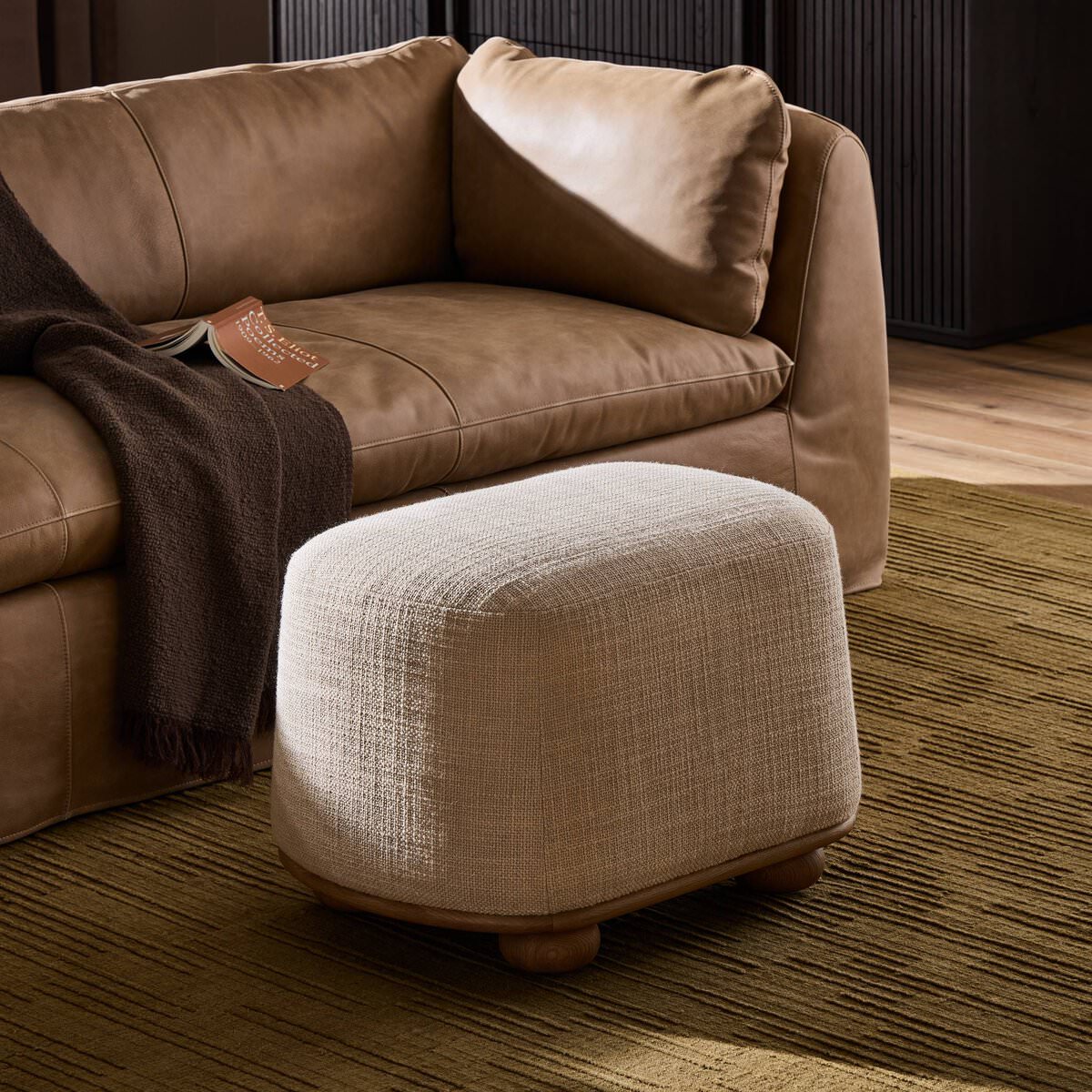 Four Hands Bilbury Oval Ottoman in Saxon Sand in a living room at Addison West