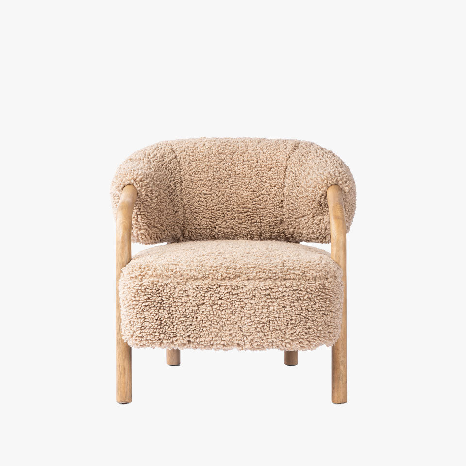 Four Hands Brodie Chair In Andes Toast with sheepskin like upholstery and wood frame on a white background
