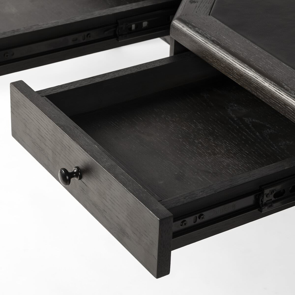 Close up of Four Hands Claude Desk in Distressed Black Oak Veneer on a white background at Addison West