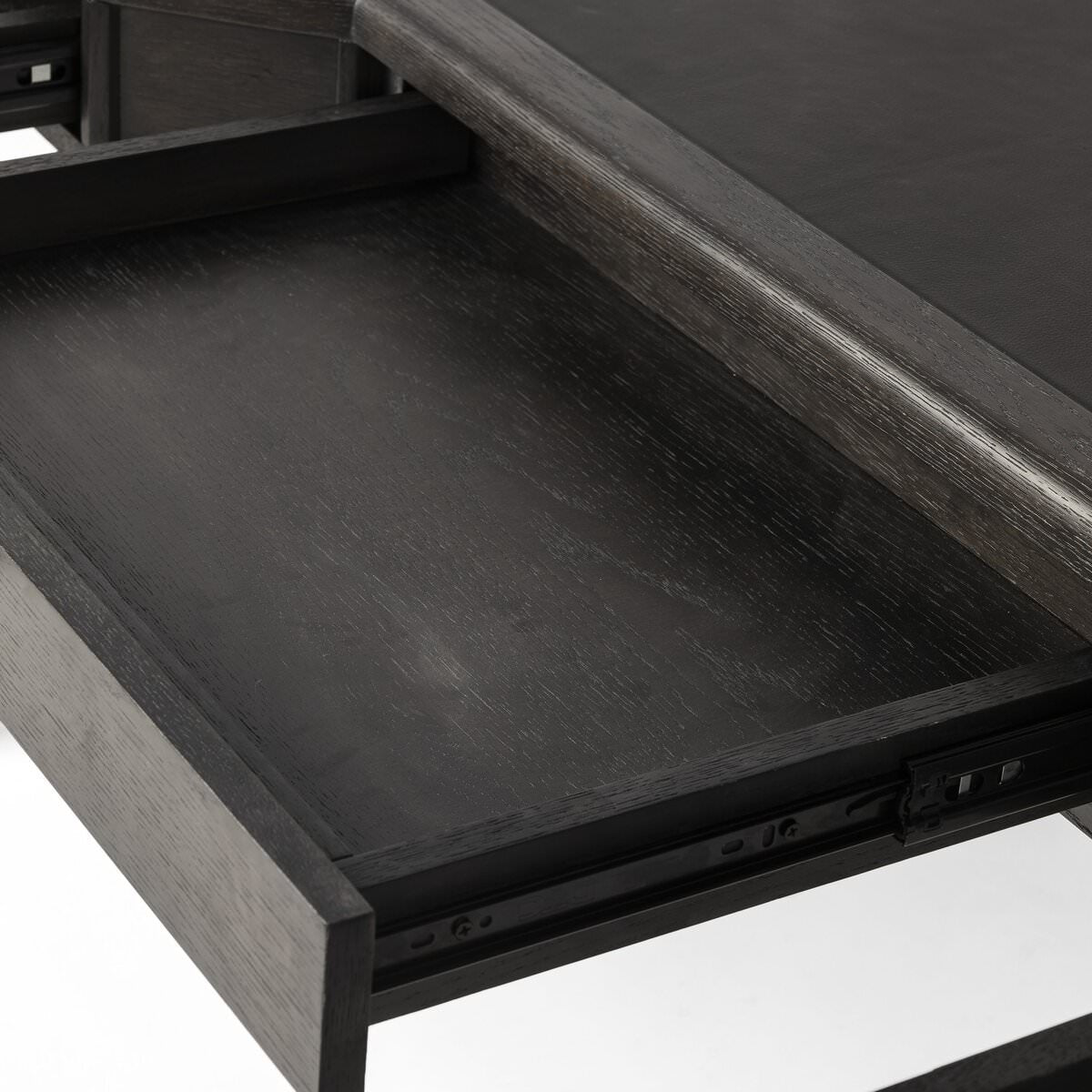 Close up of Four Hands Claude Desk in Distressed Black Oak Veneer on a white background at Addison West