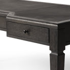 Close up of Four Hands Claude Desk in Distressed Black Oak Veneer on a white background at Addison West