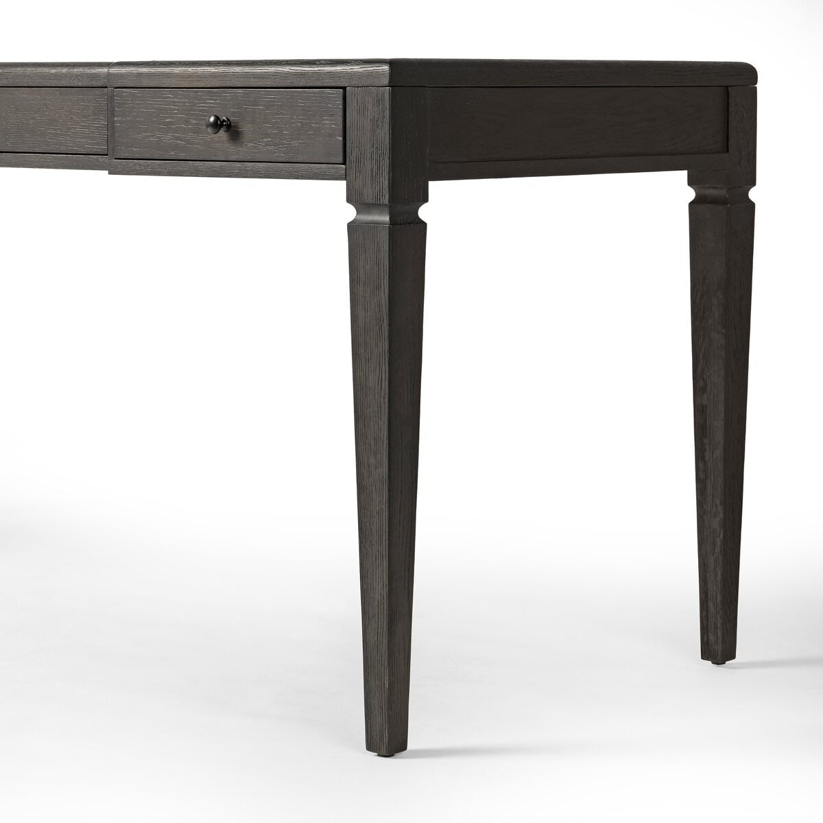 Close up of Four Hands Claude Desk in Distressed Black Oak Veneer on a white background at Addison West