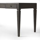 Close up of Four Hands Claude Desk in Distressed Black Oak Veneer on a white background at Addison West