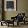 Four Hands Halston Chair + Ottoman In Heirloom Black in a moody living space with olive green walls and subtle lighting