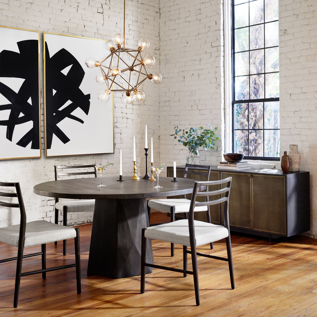 Four Hands Hendrick Sideboard with four perforated brass doors and gunmetal exterior in a loft space with white brick walls and modern dining table
