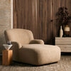 Four Hands Kadon Chaise Lounge In Sheepskin Camel in a wood panelled living space with muted rug and decor