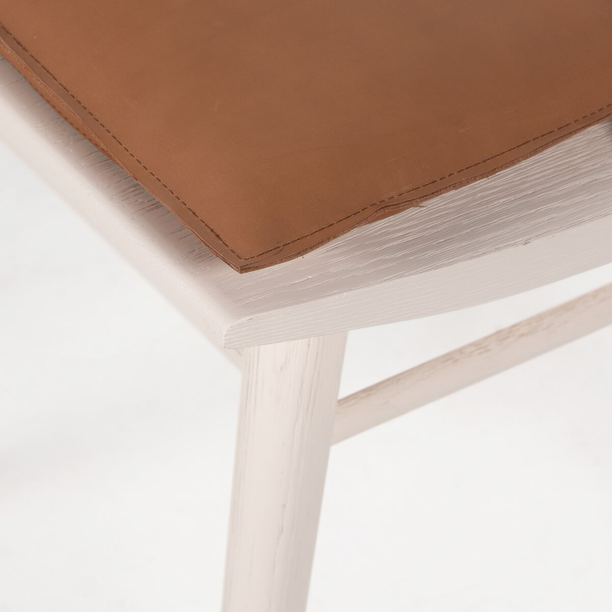 Close up of Four Hands Lewis Windsor Chair in Off White Whiskey Saddle on a white background