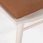 Close up of Four Hands Lewis Windsor Chair in Off White Whiskey Saddle on a white background