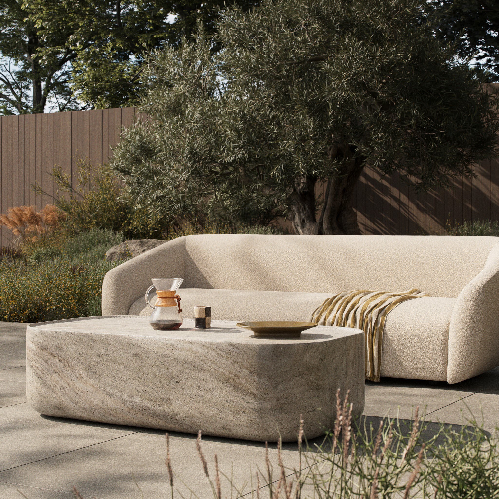 Four Hands Manor Outdoor Coffee Table in Textured Sandy Grey on a patio at Addison West