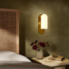 Four Hands Odyssey Sconce in Burnished Brass with Opal Matte Glass in bedroom at Addison West.