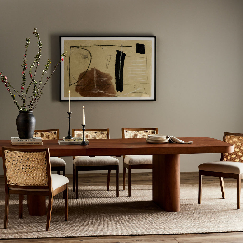 Four Hands Rufina Cherry Extendable Dining Table in a neutral dining space with cane chairs