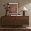 Four Hands Toulouse Sideboard In Toasted Oak in a dimly lit living space with beige walls