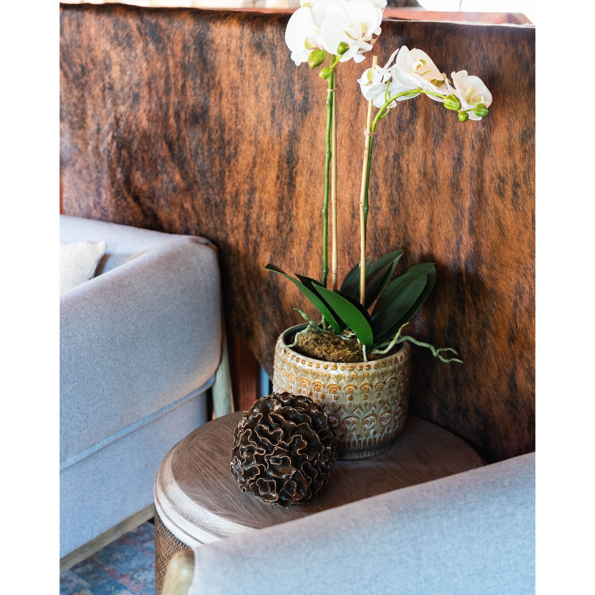 Table with potted orchid and small brown foliose sculpture