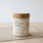 Candle labeled 'Green Mountain Morning' with a wooden lid on a textured surface.