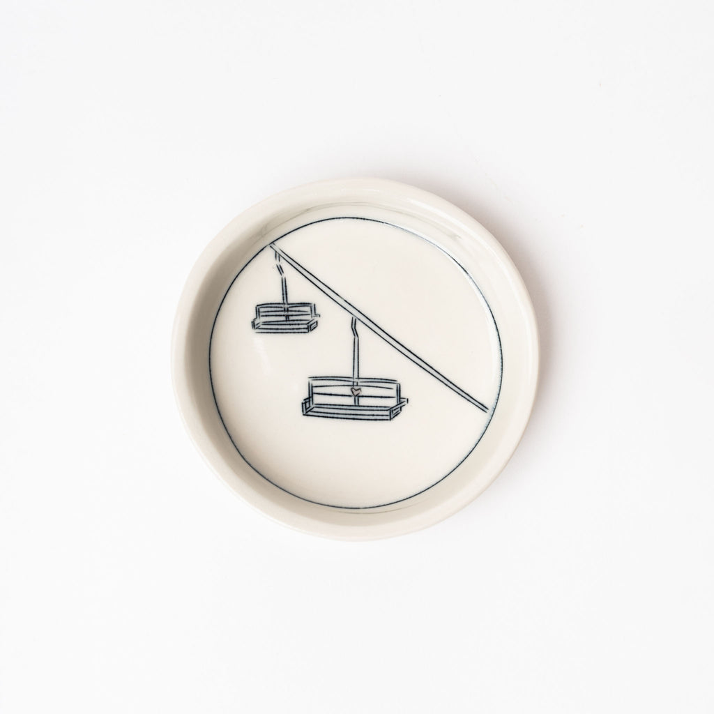 Small white handmade dish with drawing of chairlift on a white background