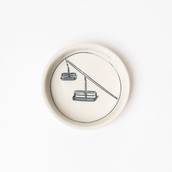 Small white handmade dish with drawing of chairlift on a white background