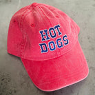 Red cap with 'HOT DOGS' text on a concrete surface