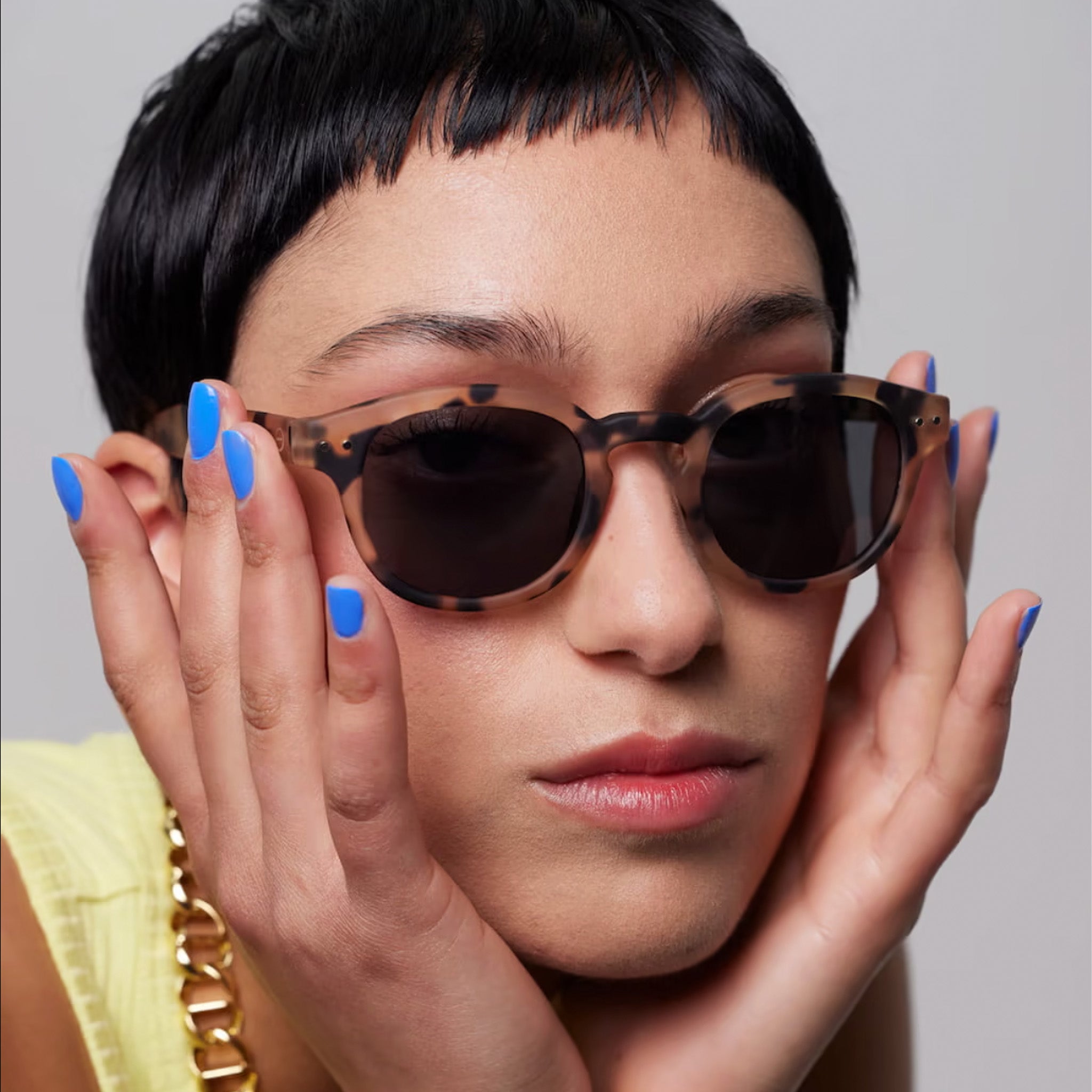 Woman wearing Izipizi #C Light Tortoise Sunglasses on plain background at Addison West.