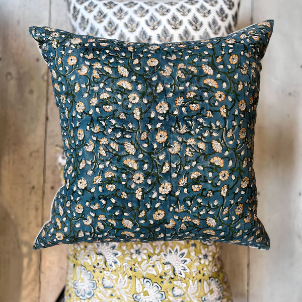 Filling spaces Izna square throw pillow on a wood floor with other complementary pillows