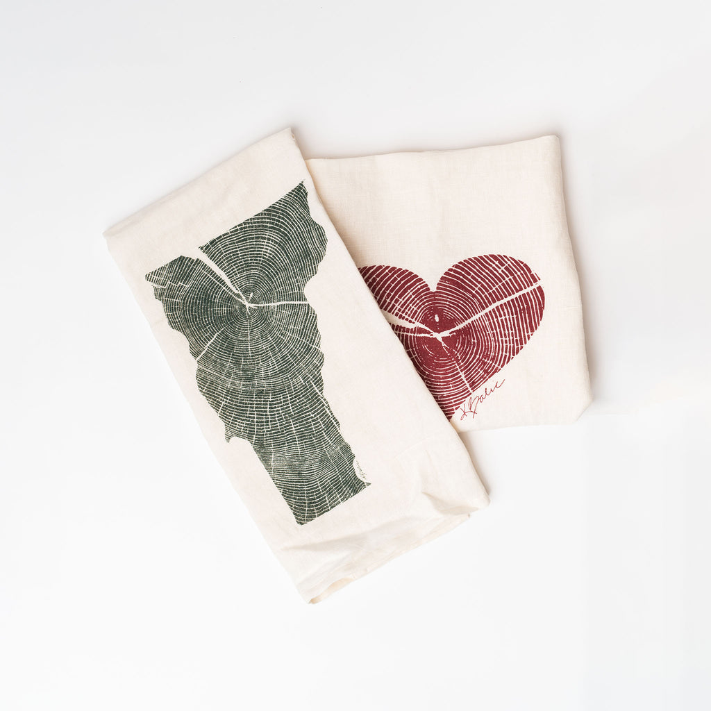 Two creme tea towels with state of vermont and red heart imprints on a white background