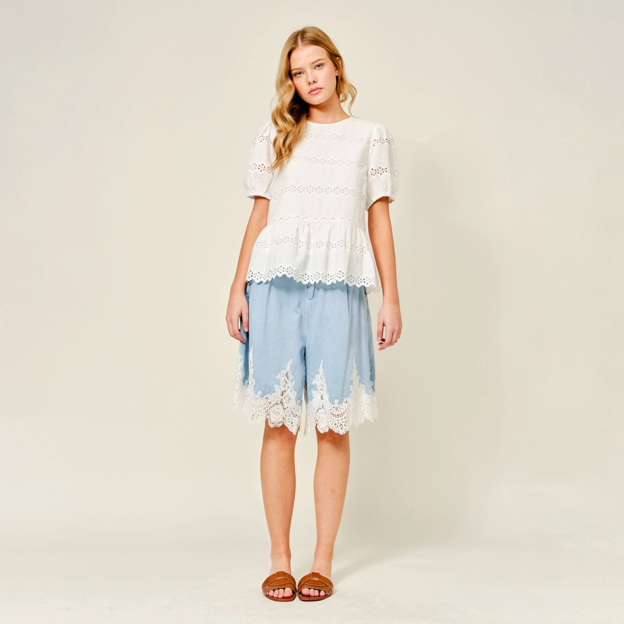 Woman wearing Aaron & Amber Lace and Scallop Hem Blouse with blue shorts on a plain background