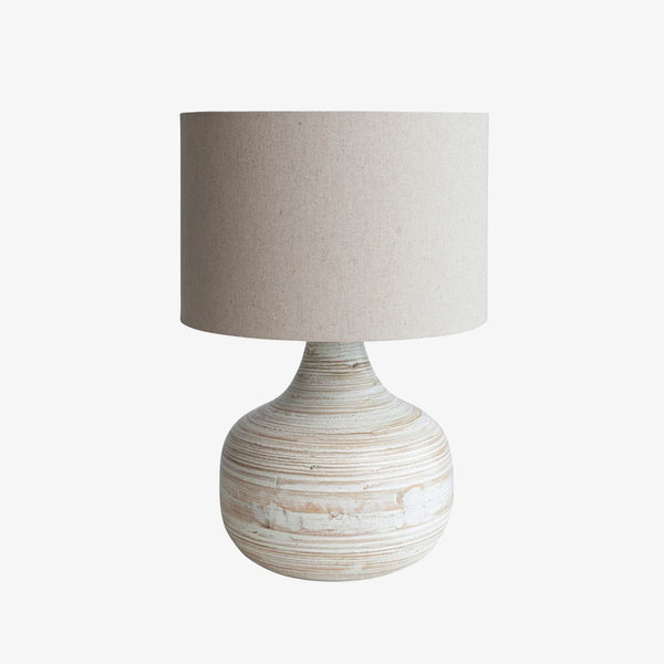 Lamp with whitewashed bamboo base and linen shade on a white background