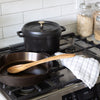 Black Staub five quart cast iron dutch oven on stove next to a cast iron pan