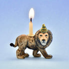 Lion-shaped candle holder with a lit candle on a light blue background