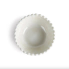 White ceramic bowl with scalloped edge on a white background