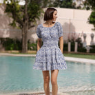 Model wearing Maison Marigold Ibiza Mini Dress in Blue in front of a pool