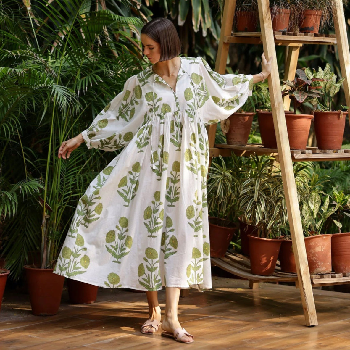 Model wearing Maison Marigold Taj Maxi Dress in Green in front of a wall of green tropical trees