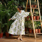 Model wearing Maison Marigold Taj Maxi Dress in Green in front of a wall of green tropical trees