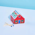 Red toy house full of matches with colorful pattern on a white surface with blue background