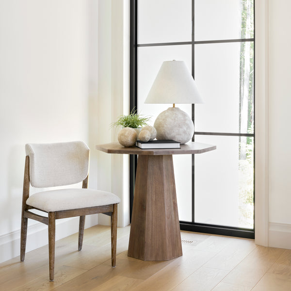 Maxine Hexagonal Wood Foyer Table in a light and airy entryway next to a window and chair