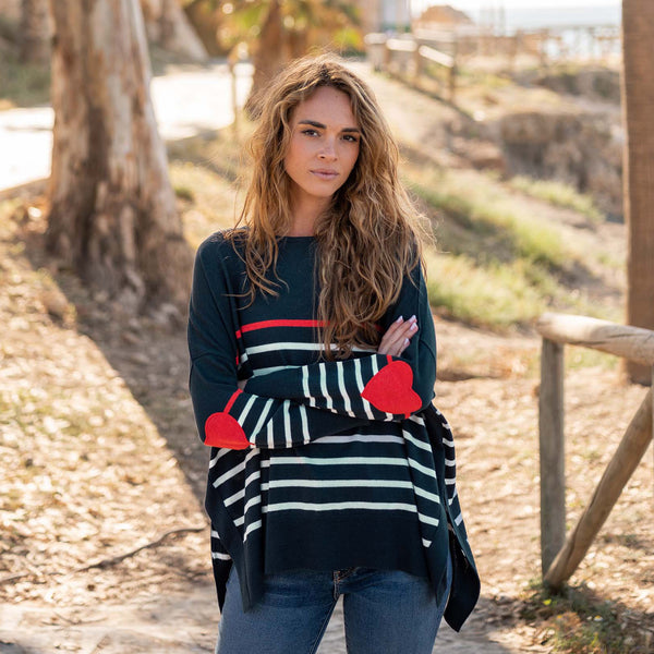Model with blond hair wearing MerSea Heart Patch Sweater in Navy Scarlet outside in a sunny wooded space