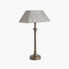 Metal candlestick style lamp with aged brass finish and rectangular linen shade.