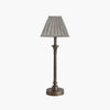 Side view of Metal candlestick style lamp with aged brass finish and rectangular linen shade.