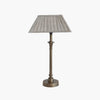 Metal candlestick style lamp with aged brass finish and rectangular linen shade on a white background