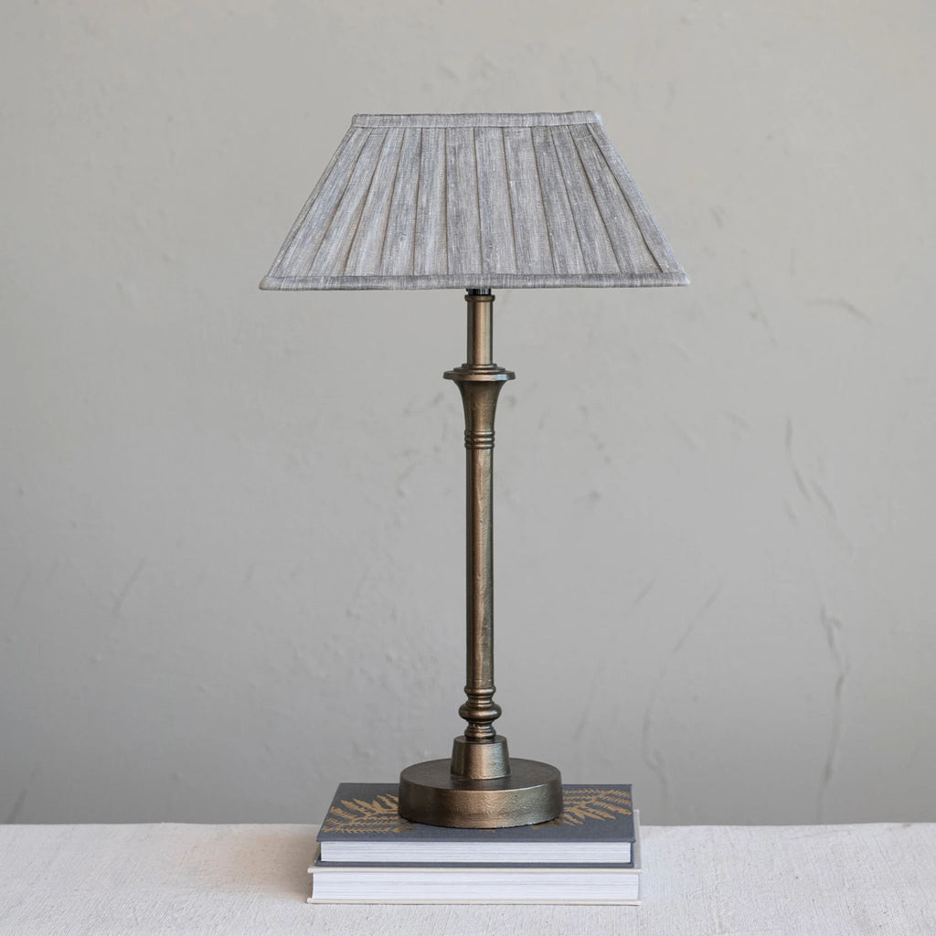 Metal candlestick style lamp with aged brass finish and rectangular linen shade.