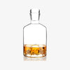 Glass decanter with mountain inset into base on a white background