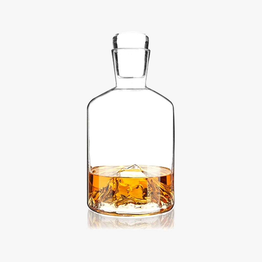 Glass decanter with mountain inset into base on a white background