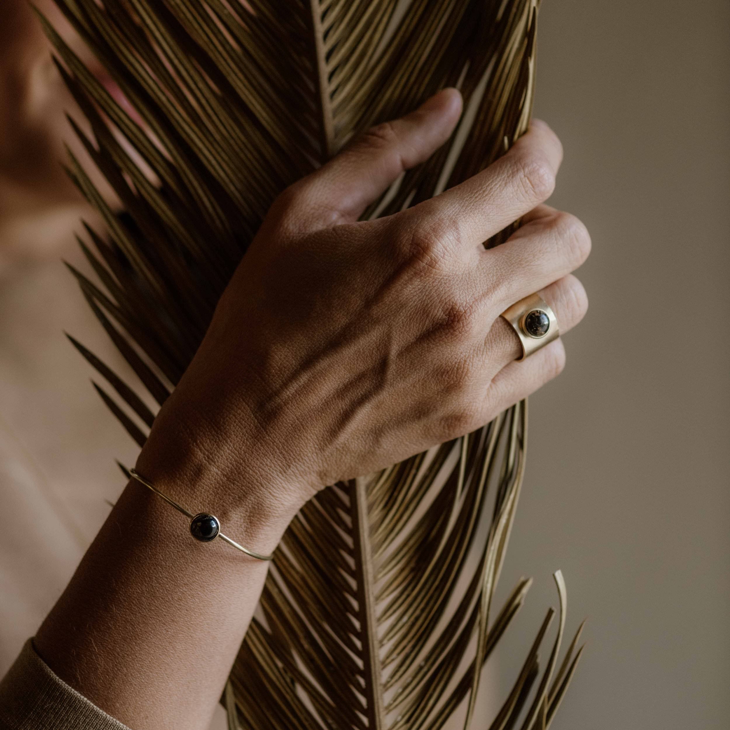 Commonform jewelry on a model's hand with a beige background at Addison West