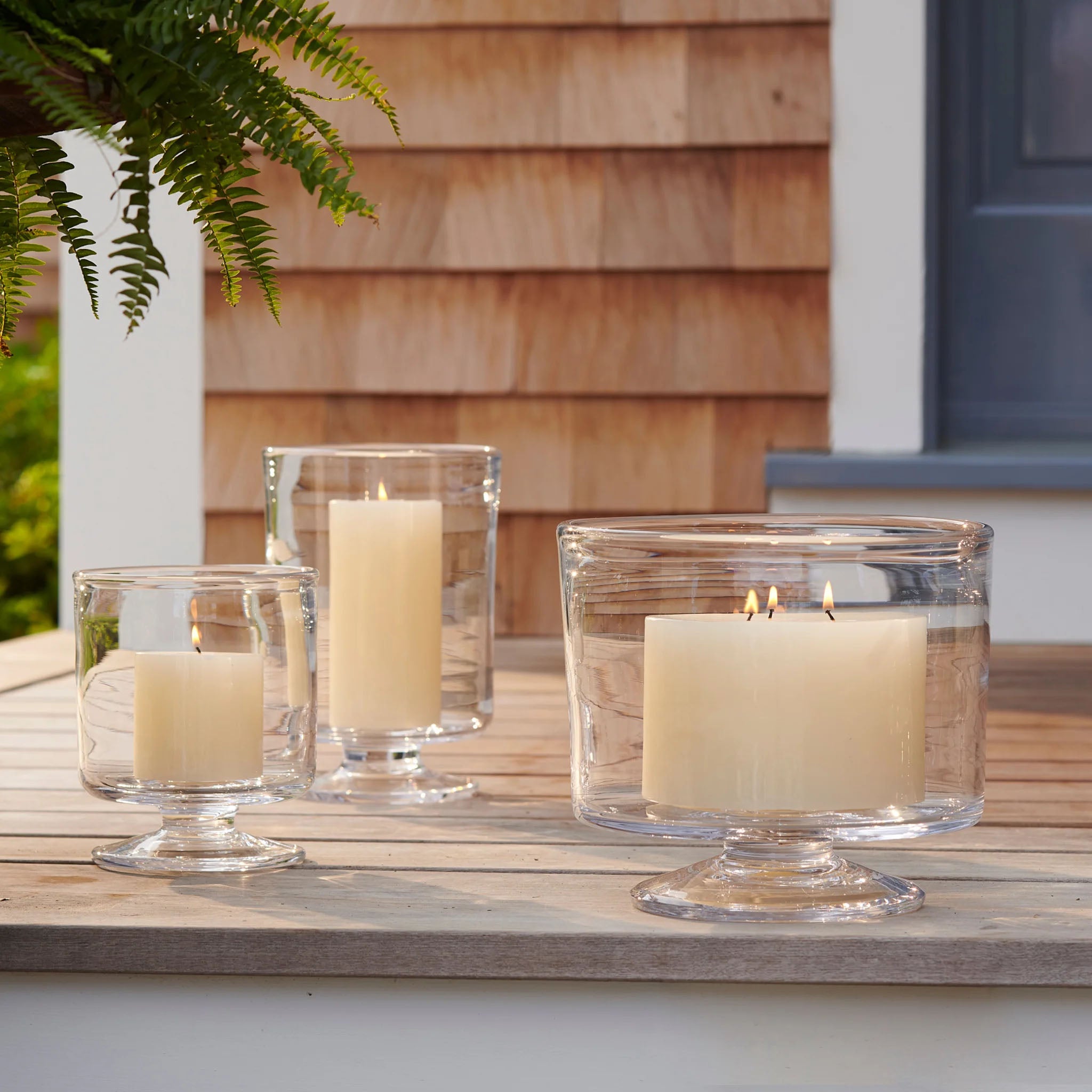 Simon Pearce Nantucket Hurricanes on a wood table outside at Addison West