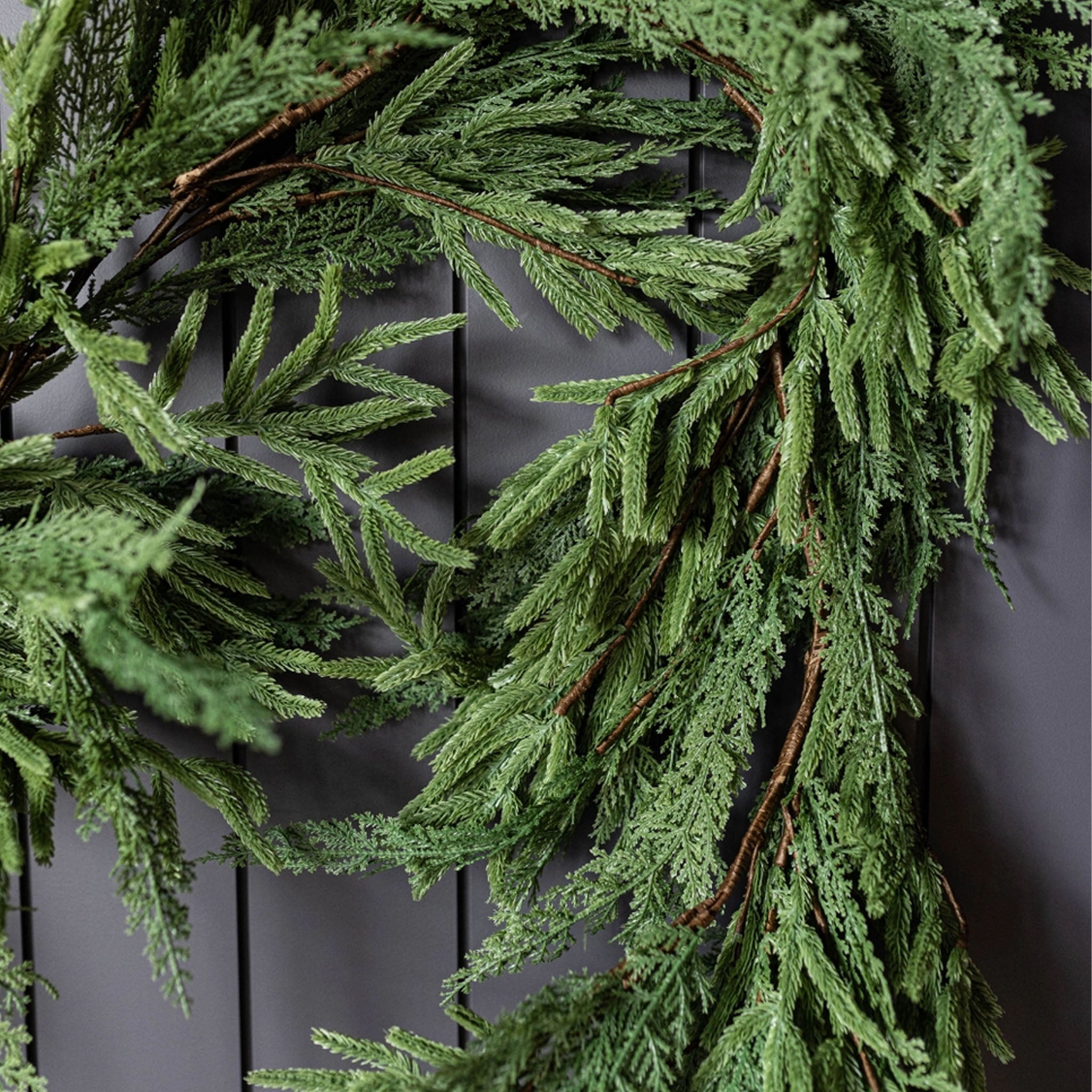 Norfolk & Cypress Mix Real Touch Faux Garland, 9ft on a black wall at Addison West